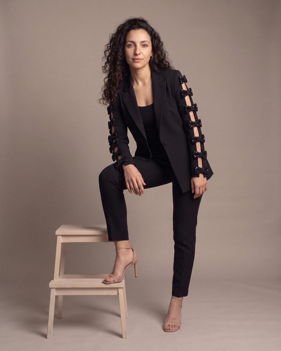 Blazer à nœuds ajourés, noir, porté, pied posé sur tabouret
