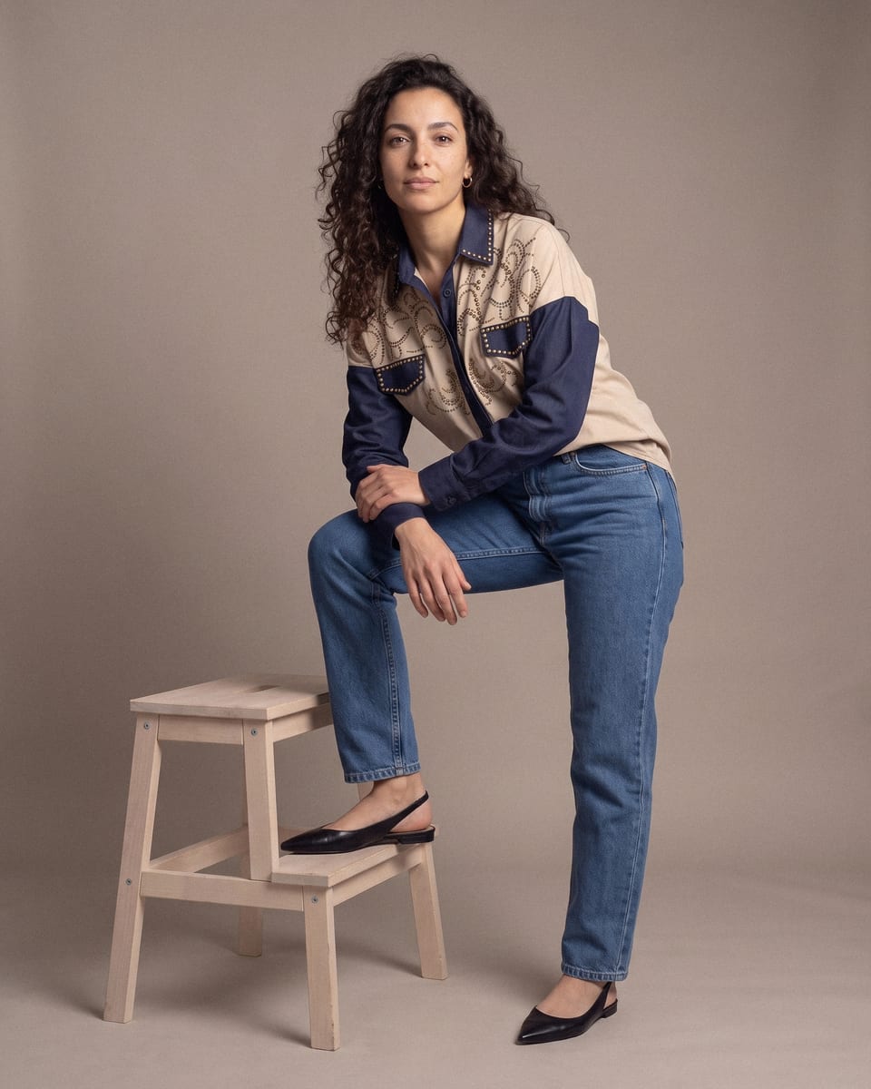 Chemise western cloutée, beige et marine, portée, pied posé sur tabouret
