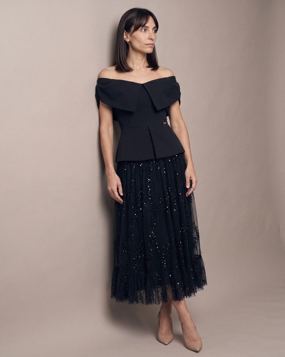 Ensemble de soirée en tulle, noir, porté, appuyée au mur, chevilles croisées