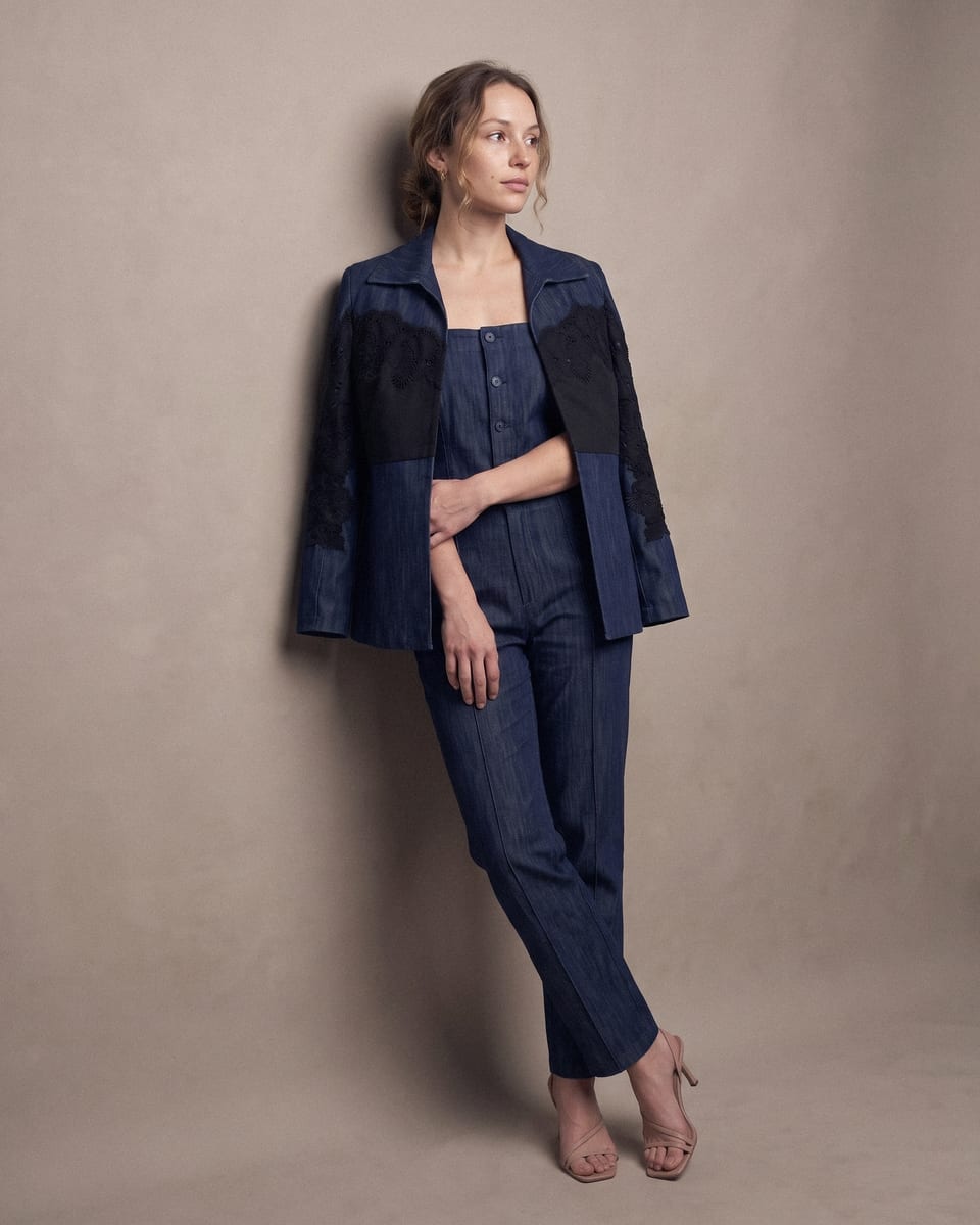 Ensemble denim brodé, bleu nuit, porté, appuyée au mur, chevilles croisées