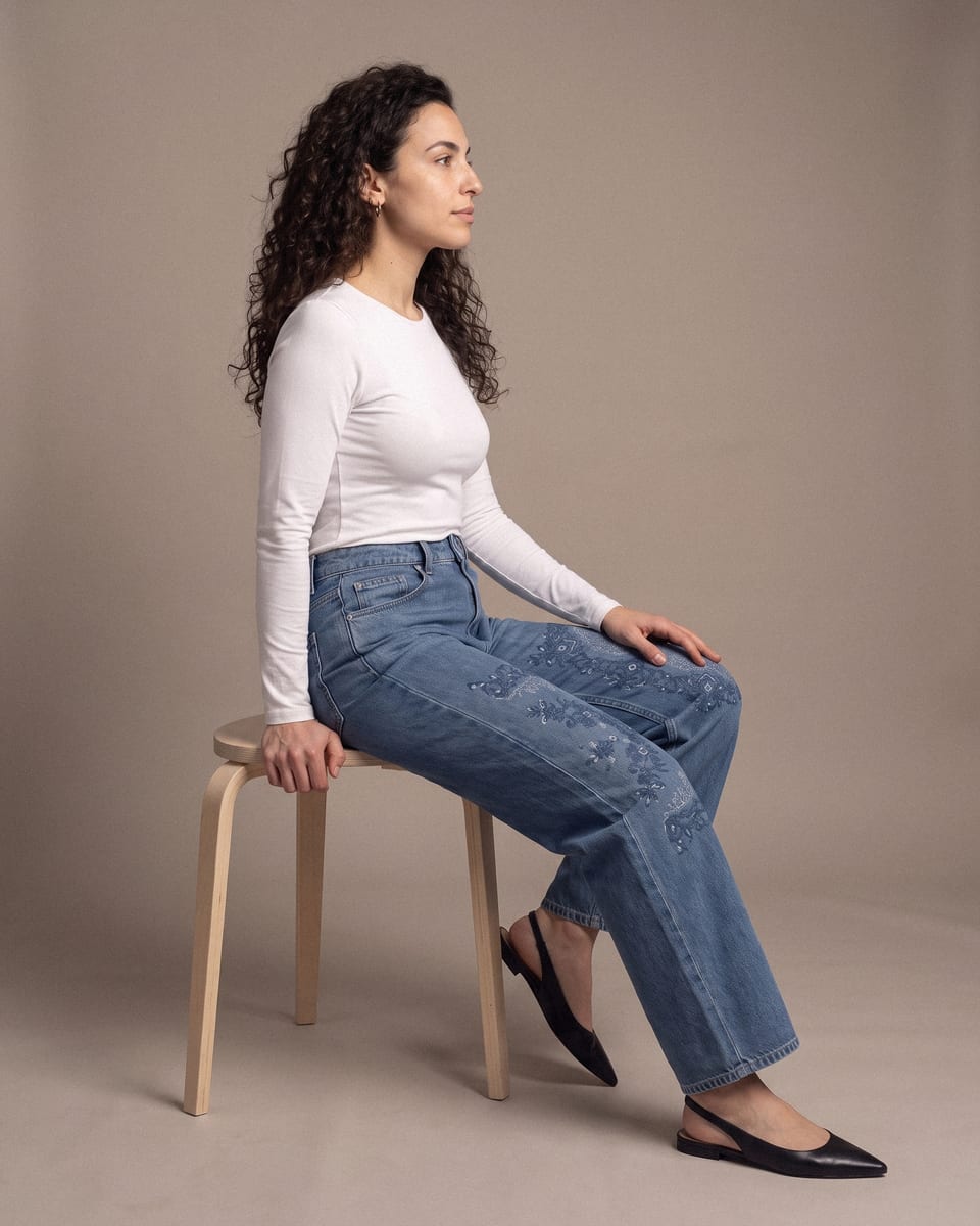 Jean large brodé, bleu, porté, assise de profil