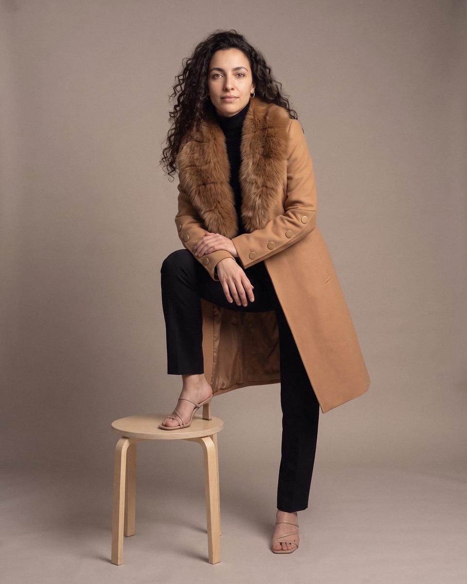 Manteau à grand col, tabac, porté, pied posé sur tabouret