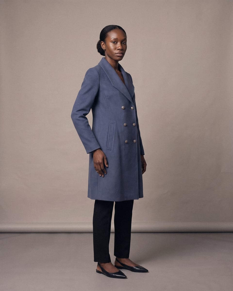 Manteau croisé ceinturé, bleu, porté, tourne la tête, cheveux en mouvement