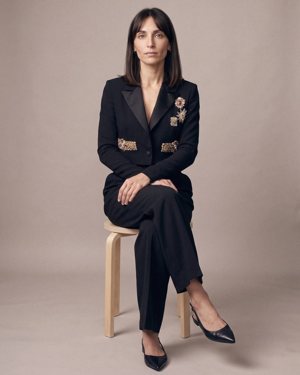 Veste courte brodée, noir, portée, assise sur tabouret, jambes croisées
